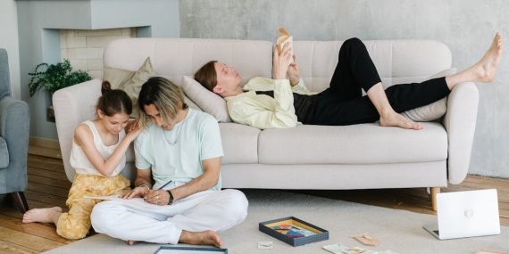 Father and daughter bonding in cozy living room with books and games, creating joyful family moments.